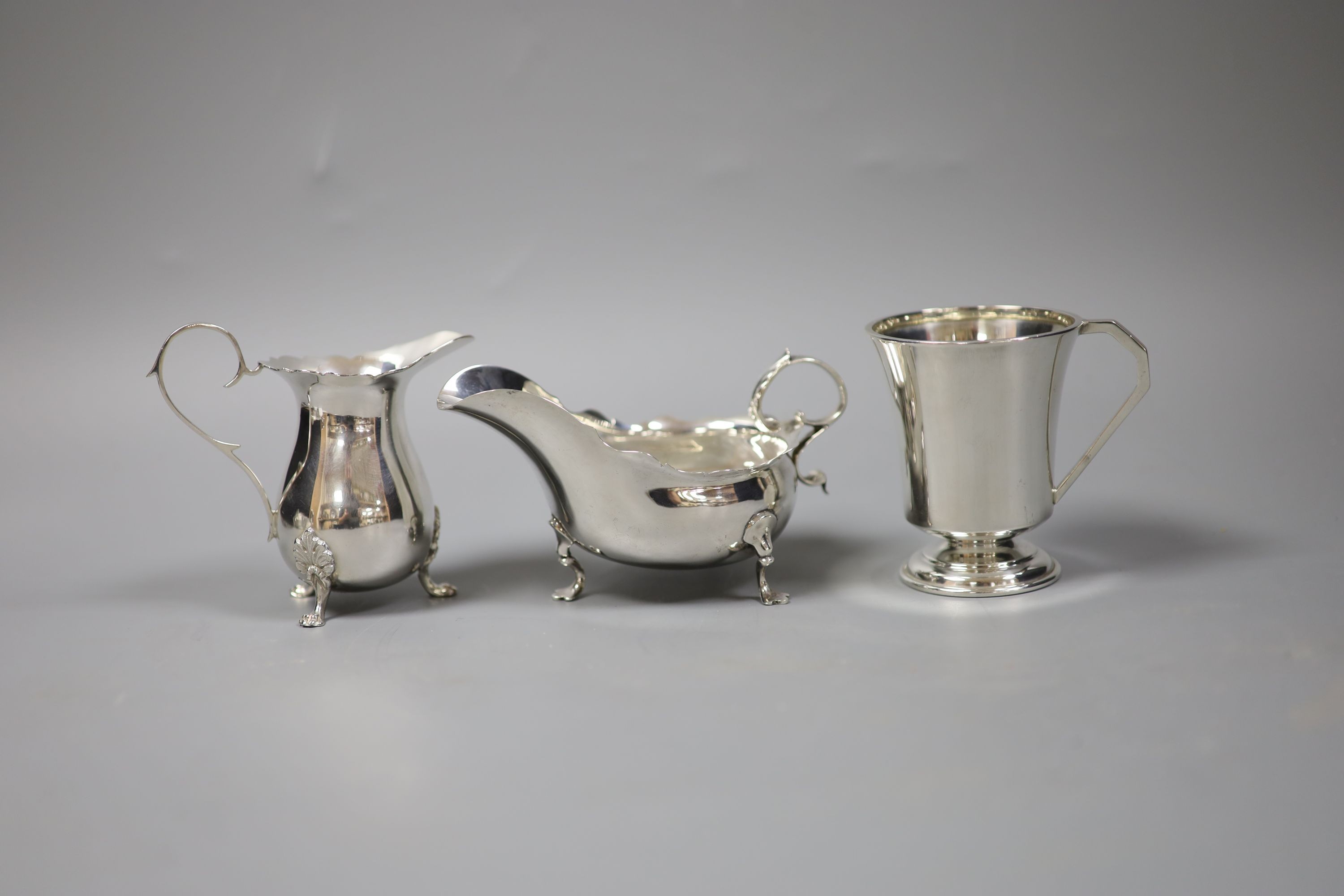 An Edwardian silver sauce boat, London, 1901 and a later silver cream jug and mug, 9oz.